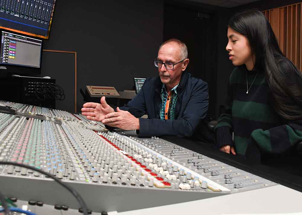 Audio engineering student with instructor on soundboard