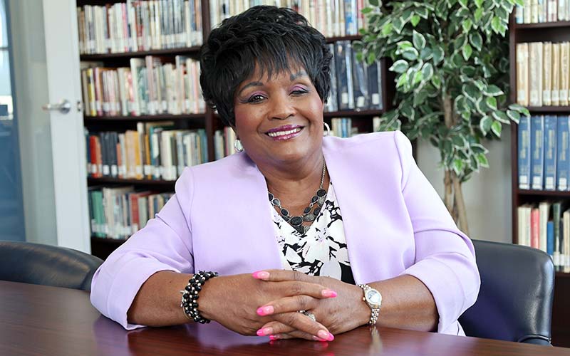 Older San Jacinto College student Dessie Gipson sitting at a table with hands crossed