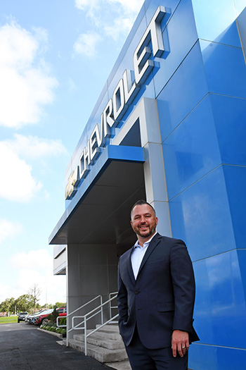 Alumnus Lenny Gordon standing outside Chevrolet dealership