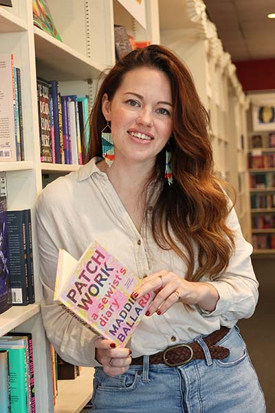Woman holding book and leaning against a bookshelf