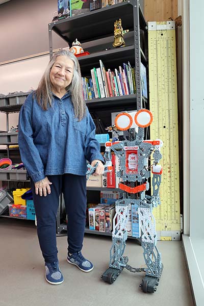 Math professor Sharon Sledge standing next to robot in robotics lab